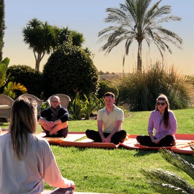 Gruppe bei einer geführten Meditation im Garten der Finca Can Ferragut mit Blick auf die Landschaft